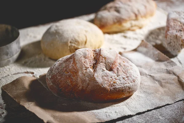 Bröd och deg på köksbordet i mörkret — Stockfoto