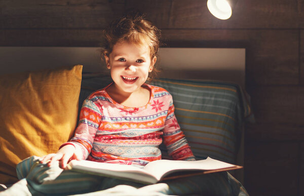 Девочка читает книгу в постели
  