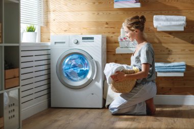 Happy housewife woman in laundry room with washing machine  clipart