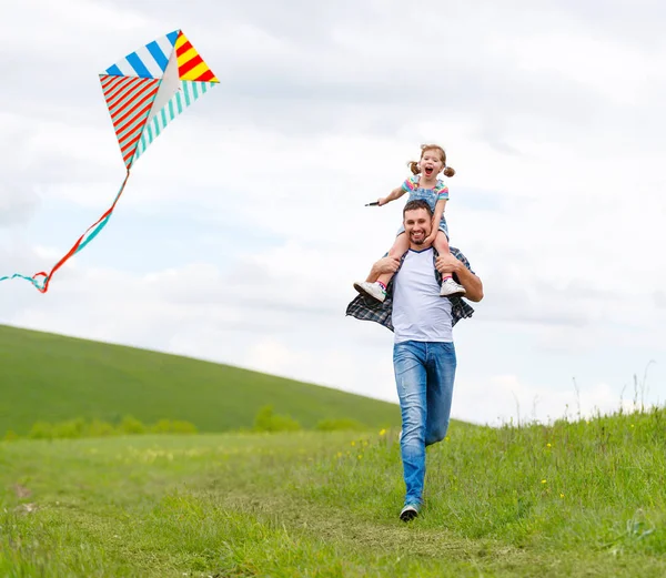 Счастливый отец семьи и ребенок дочь запустить с воздушным змеем на лугу — стоковое фото