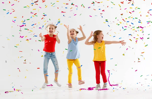 Enfants heureux en vacances sautant dans des confettis multicolores sur — Photo