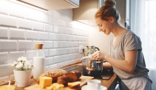 Молодая женщина в пижаме готовит завтрак утром — стоковое фото