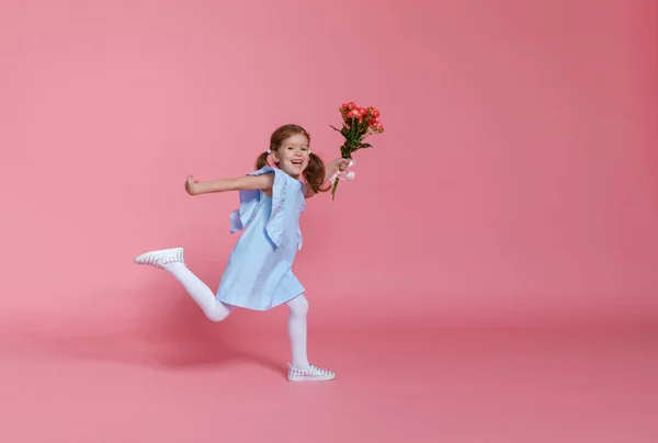 Criança engraçada menina corre e salta com buquê de flores na cor — Fotografia de Stock