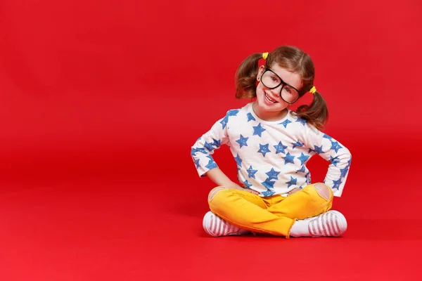 Grappige kind meisje in glazen op gekleurde achtergrond — Stockfoto