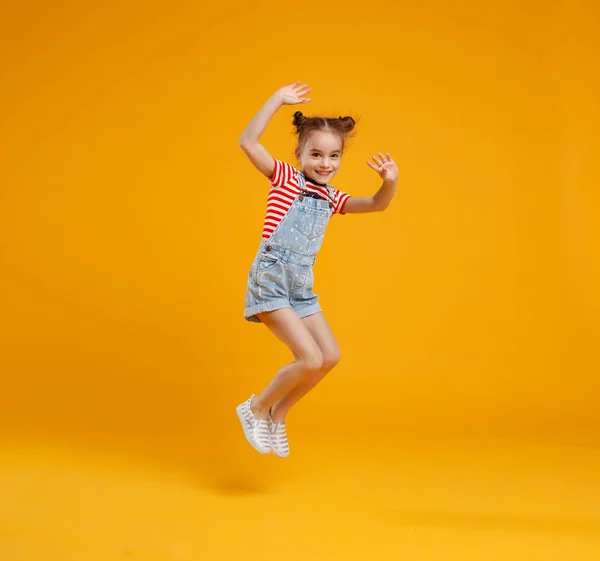 Menina engraçada pulando no fundo amarelo colorido — Fotografia de Stock