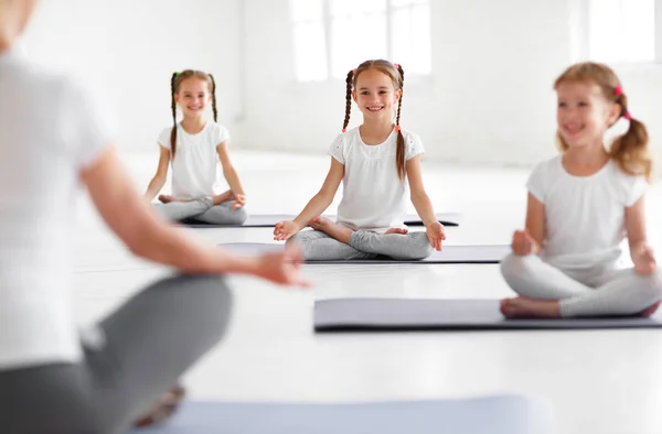 Bambini che praticano yoga in una posa di loto con insegnante — Foto Stock
