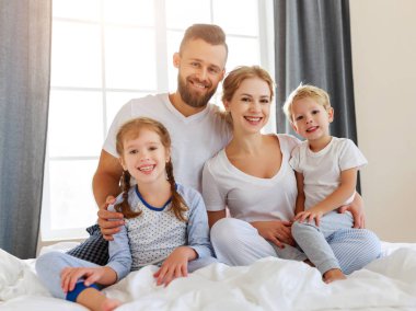 Mutlu aile anne, baba ve çocuklar gülüyor, oynuyor ve...