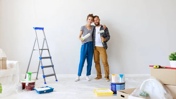 Молодая счастливая пара ремонтирует и красит стены в доме — стоковое фото