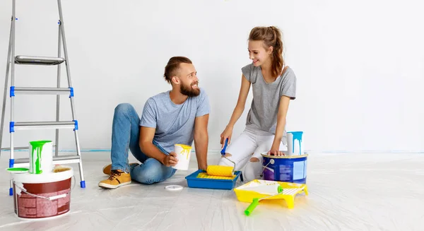 Joven feliz pareja está reparando y pintando la pared en hom — Foto de Stock