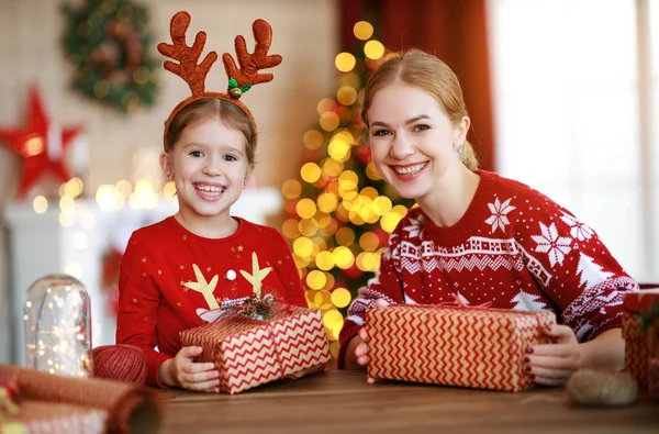 Щаслива родина мати і дитина упаковують різдвяні подарунки вдома поруч — стокове фото