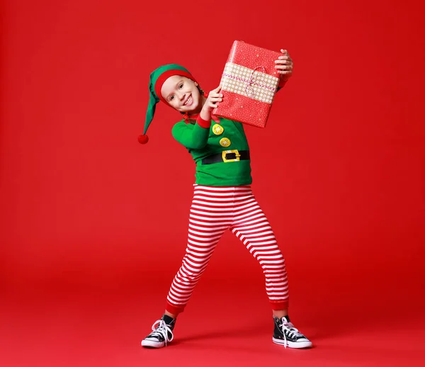 Alegre divertido bebé en traje de elfo de Navidad con regalos en rojo — Foto de Stock