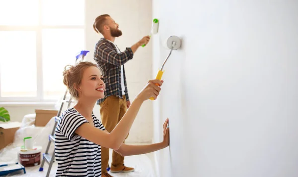 Jovem casal feliz está reparando e pintura parede em casa — Fotografia de Stock