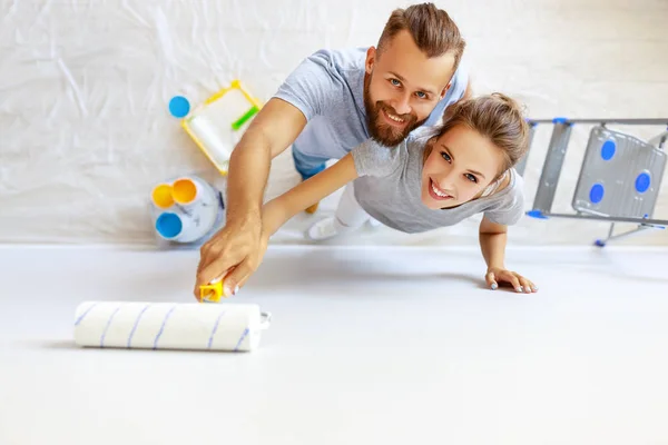 Young happy couple is repairing and painting   wall at home — ストック写真