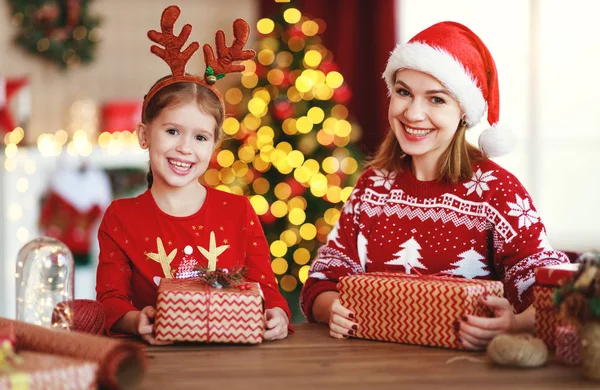 Щаслива родина мати і дитина упаковують різдвяні подарунки вдома поруч — стокове фото