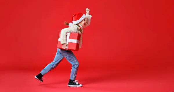 Glad rolig barn flicka med julklapp på röd backgroun — Stockfoto