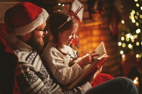 Напередодні Різдва. сім'я батько і дитина читають чарівну книгу вдома — стокове фото