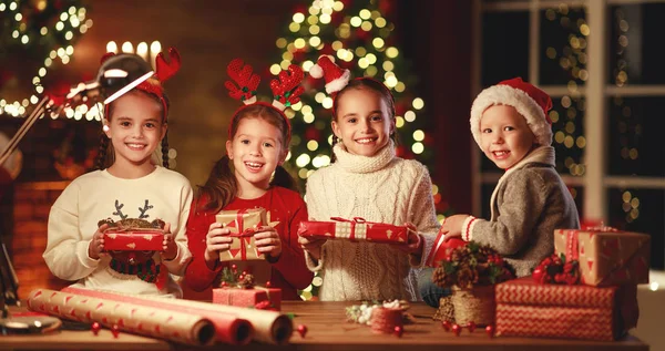 Felice divertente bambini ragazze imballare regali di Natale alla sera in ho — Foto Stock