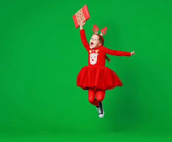 Happy funny child girl in red Christmas reindeer costume jumping — Stock Photo, Image