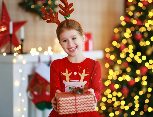 Щаслива смішна дівчинка з різдвяним подарунком вдома — стокове фото