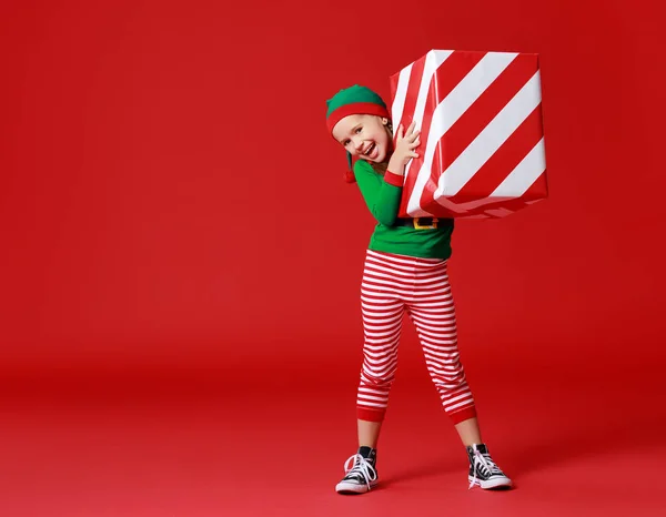 Criança engraçada alegre em traje de duende de Natal com presentes em re — Fotografia de Stock