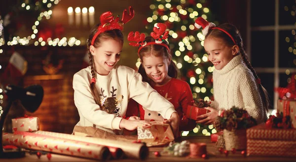 Felice divertente bambini ragazze imballare regali di Natale alla sera in ho — Foto Stock