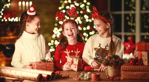 Щасливі смішні діти дівчата пакують різдвяні подарунки ввечері в го — стокове фото