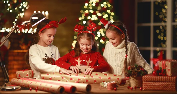 Happy funny children girls pack Christmas gifts at evening in ho — Stock Photo, Image