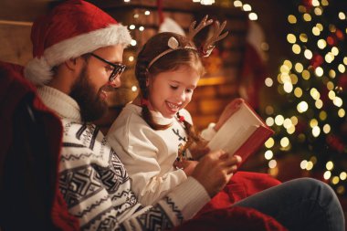 Noel arifesi. Aile babası ve çocuk evde büyü kitabı okuyorlar.