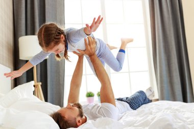 Mutlu aile babası ve kızı evde, yatakta.  