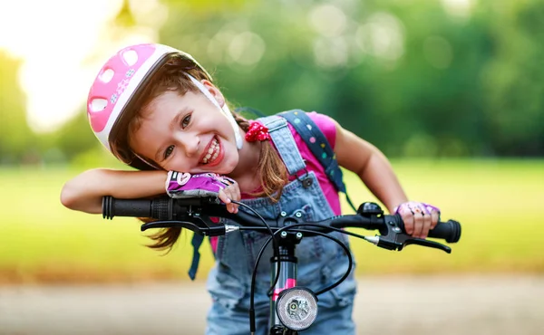 Fröhliches, fröhliches Kindermädchen auf einem Fahrrad im Park in der Natur — Stockfoto