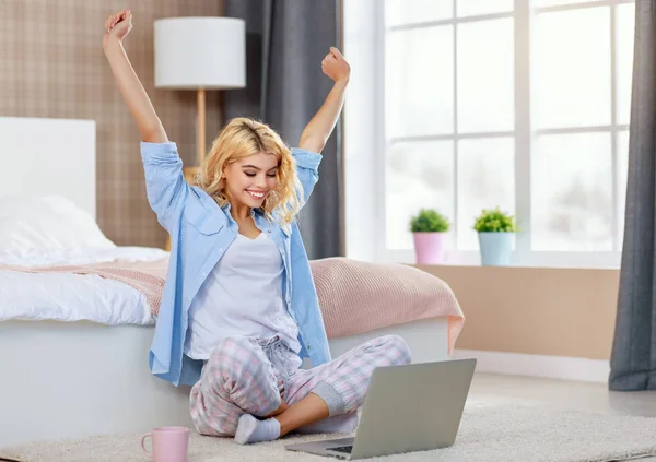 Jovem feliz com computador em casa na cama trabalhando e laug — Fotografia de Stock