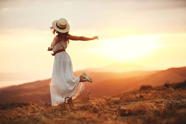 Mulher feliz de pé com as costas no pôr do sol na natureza — Fotografia de Stock