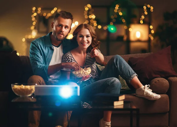 Coppia di famiglie che guarda il proiettore televisivo a casa sul divano — Foto Stock