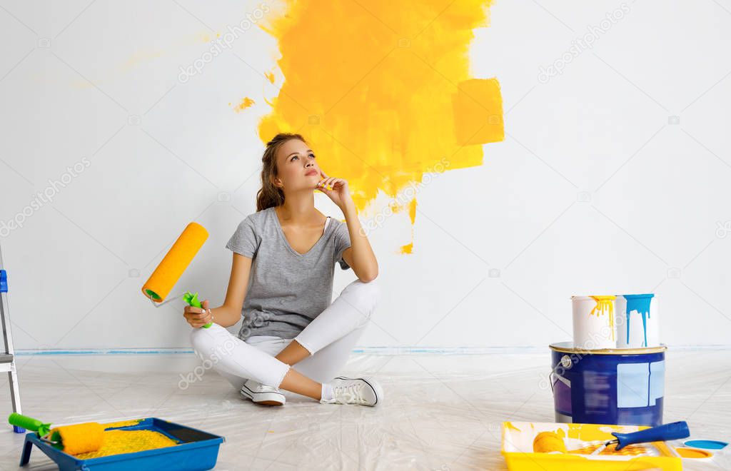 Repair in apartment. Happy young woman paints wall