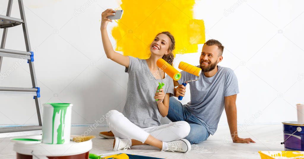 young happy couple is repairing and painting   wall at hom