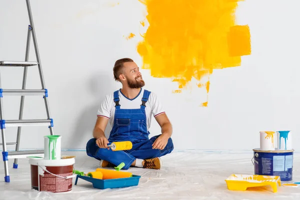 Reparação em apartamento. Homem feliz trabalhador pinta parede — Fotografia de Stock