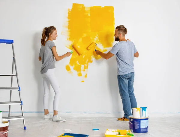 Jovem casal feliz está reparando e pintura parede em hom — Fotografia de Stock