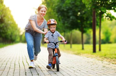 mutlu aile annesi Parkta bisiklete binmek için çocuk oğlu öğretir