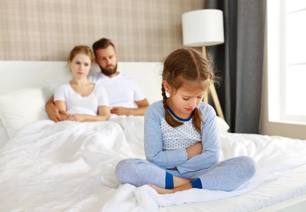 Offended upset sad child girl in bed with parents — Stock Photo, Image