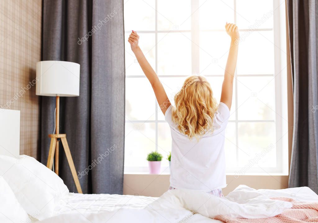 cute girl wakes up in her bedroom and stretching in the mornin
