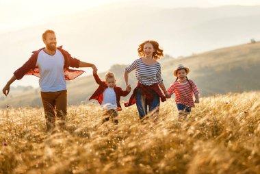 Mutlu aile: anne, baba, çocuk, oğul ve kız koşuyor.