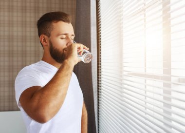 Genç ve sağlıklı bir adam sabahları su içiyor.