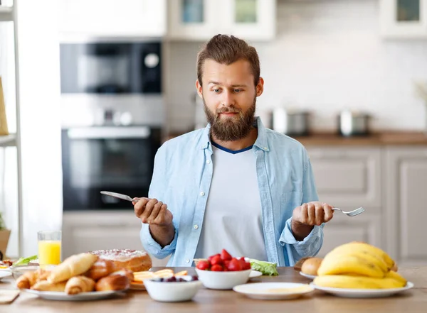 若い健康な男は家で台所で昼食を食べる — ストック写真