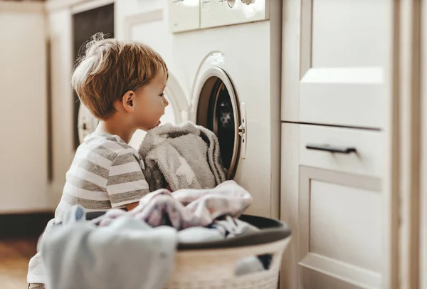 Gelukkig huishouden kind jongen in wasserij met wassen machin — Stockfoto