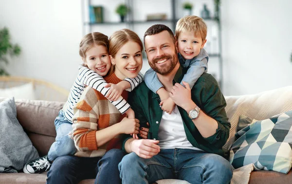 Boldog család anya apa és a gyerekek otthon a kanapén — Stock Fotó