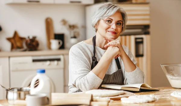 Glad gammal kvinna mormor kockar i köket knådar deg, bakar kock — Stockfoto