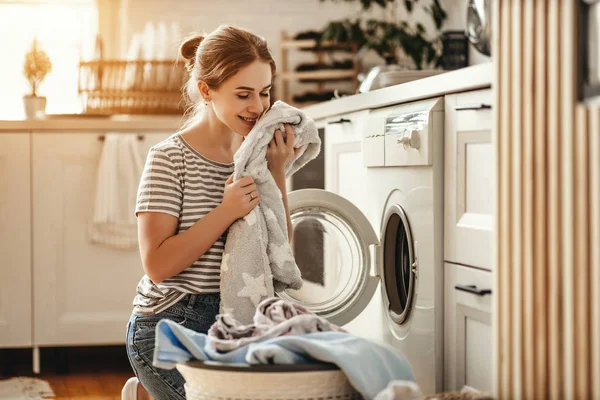 Mulher dona de casa feliz na lavanderia com máquina de lavar roupa — Fotografia de Stock