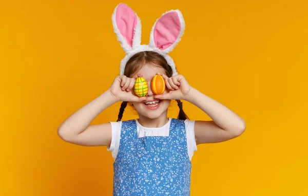 Drôle fille heureuse enfant avec des œufs de Pâques sur jaune — Photo