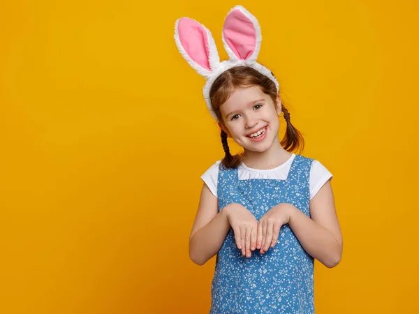 Divertida niña feliz con orejas de Pascua de conejo en amarillo — Foto de Stock