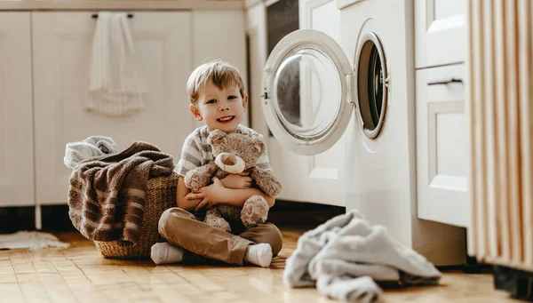 Šťastný domácí chlapec v prádelně s pračkou — Stock fotografie